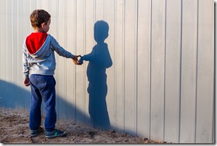 boy and his shadow. Lonely little child playing with his shadow outside. imaginary friend. the concept of autism and loneliness. Copy space for your text