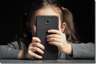 Problem of kids addiction to gadgets, online and screen time. Little girl with big smartphone in her hands