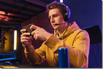 Young pro gamer playing in online mobile video games in neon coloured room