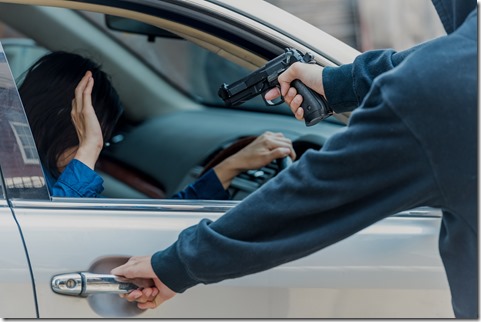 Robber threatened driver car on street. Thief use gun to intimidate asian woman for give car key. Give rob car key by thief cover face with black mask, intimidate by pointing gun.