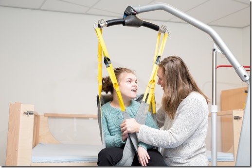 Disability a disabled child being cared for / Disability a disabled child being cared for by a special needs carer using specialist lifting equipment