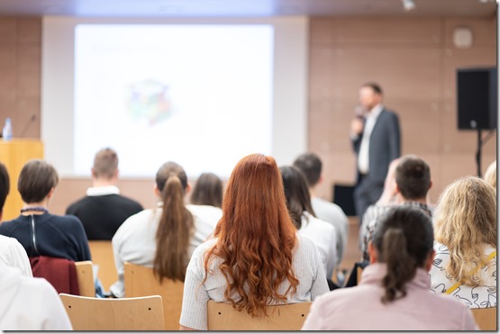 Speaker giving a talk in conference hall at business event. Rear view of unrecognizable people in audience at the conference hall. Business and entrepreneurship concept