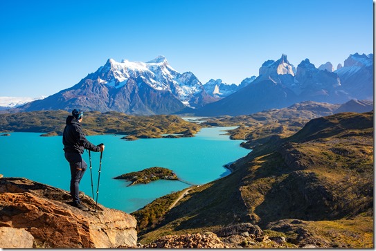 Hiker at mirador condor enjoying amazing view of Los Cuernos rocks and Lake Pehoe in Torres del Paine national park, Patagonia, Chile